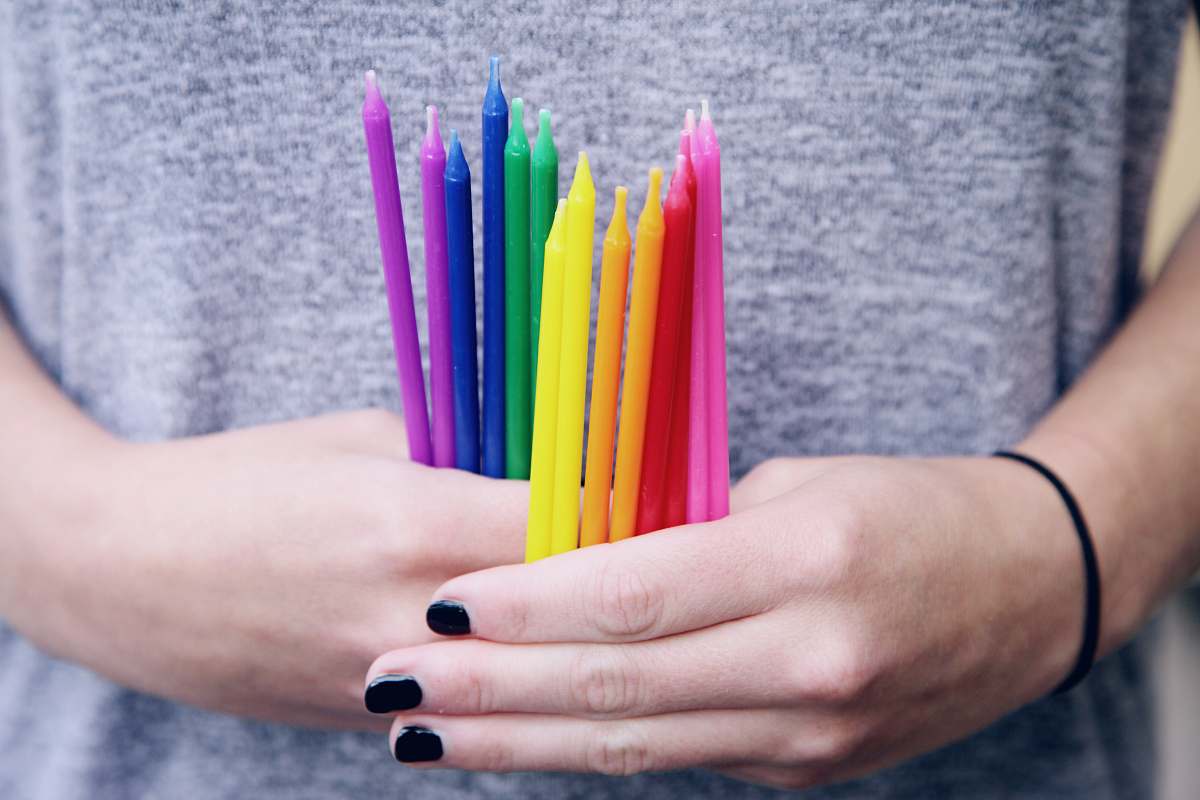 united states person holding assorted-color candlesticks birthday candle
